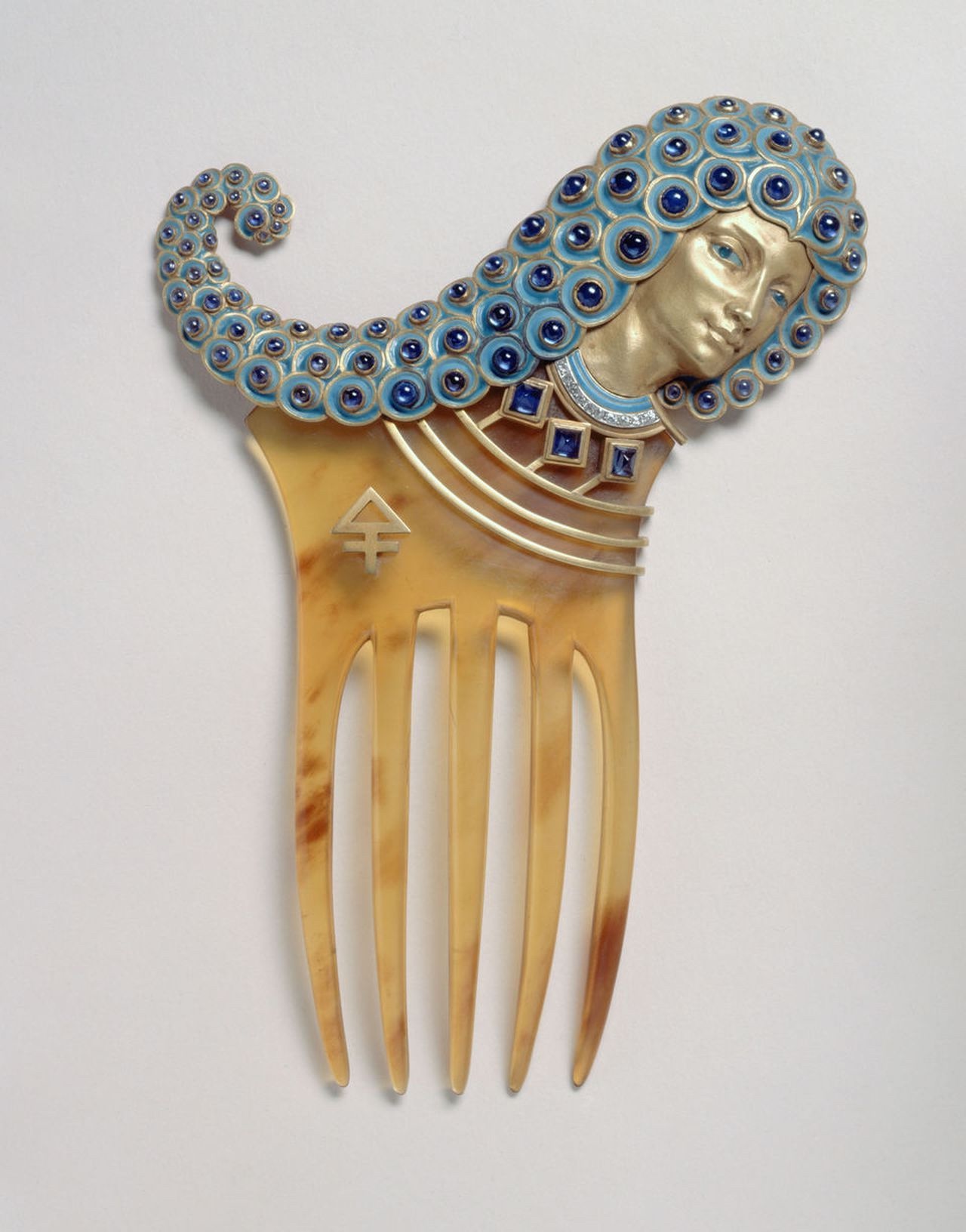 An intricate Art Nouveau hair comb design by Eugène Grasset, featuring an 'Assyrian' woman's profile with a stylized headdress embellished with blue circles.