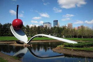 Spoonbridge and Cherry (1988) reflects a giant gray spoon spanning a shallow pond