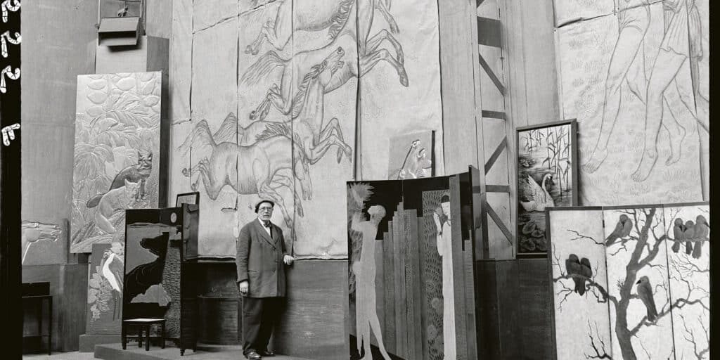 Jean Dunand alongside some of his paintings