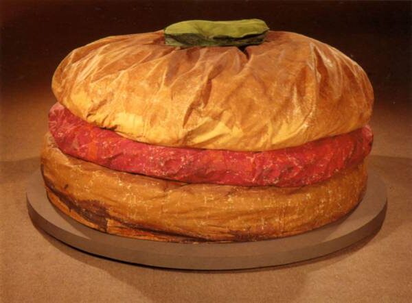 Floor Burger (Giant Hamburger) (1962) by Claes Oldenburg reflects an oversized, soft sculpture of a hamburger, made from painted canvas stuffed with foam and cardboard